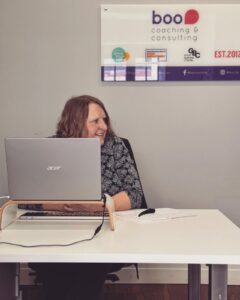 A woman sitting in front of a computer, smiling